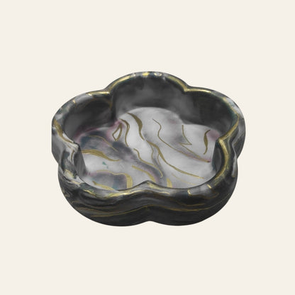 Bandeja decorativa AIKO con forma de flor en tonos oscuros veteados y detalles dorados para organizar accesorios.