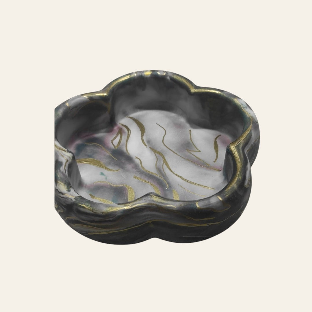 Bandeja decorativa AIKO con forma de flor en tonos oscuros veteados y detalles dorados para organizar accesorios.
