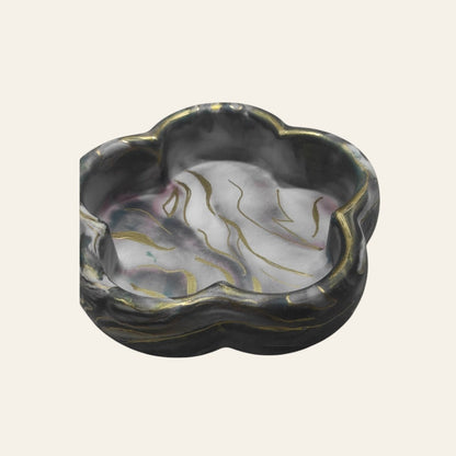 Bandeja decorativa AIKO con forma de flor en tonos oscuros veteados y detalles dorados para organizar accesorios.