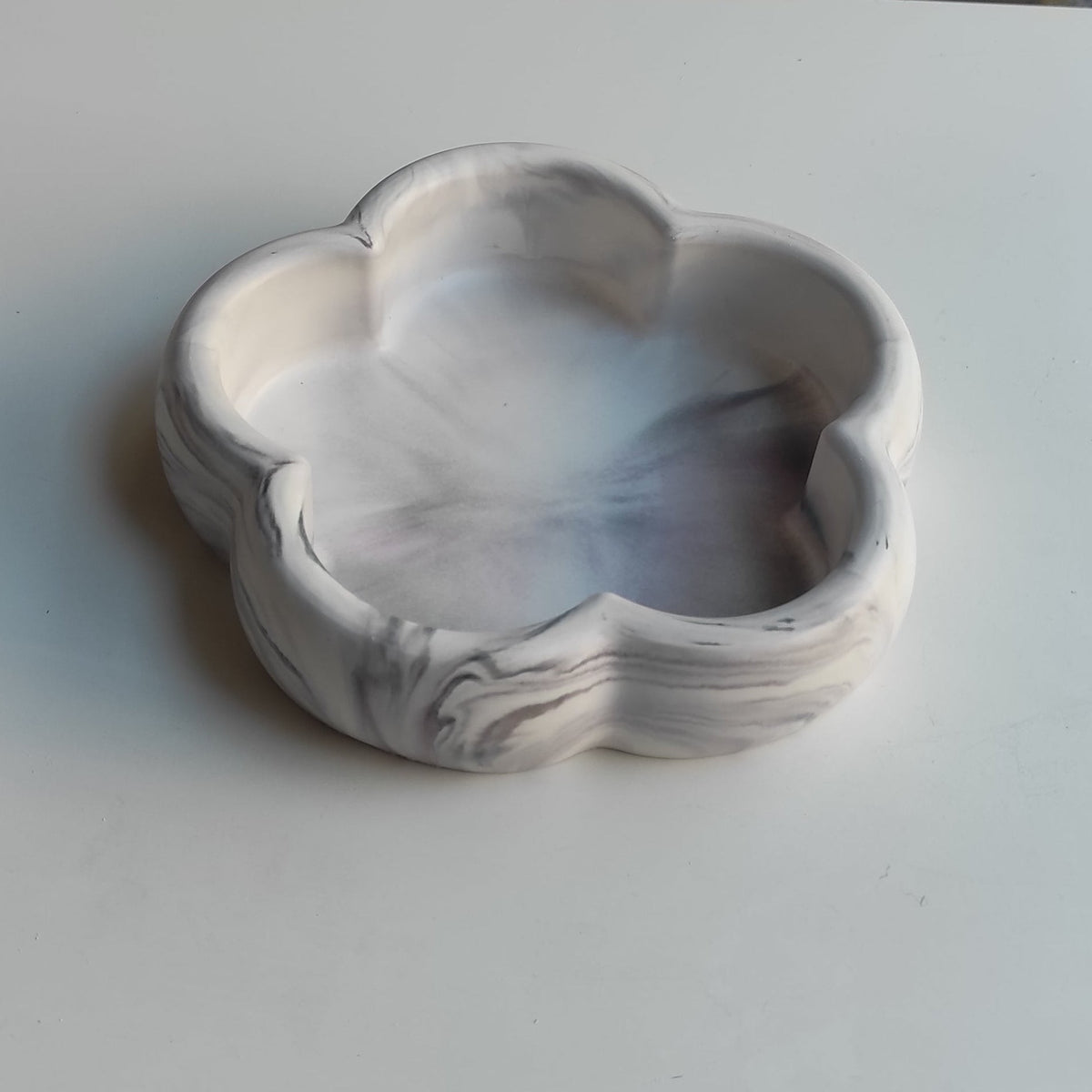Bandeja decorativa AIKO con forma de flor y acabado marmolado en tonos gris y blanco para organizar accesorios.