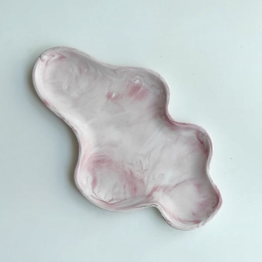 Bandeja decorativa AIKO con forma de nube irregular, fabricada en resina con acabado efecto mármol en tonos rosa y blanco.