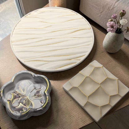 Conjunto de tres bandejas decorativas AIKO con formas geométricas y orgánicas en tonos neutros con detalles dorados.