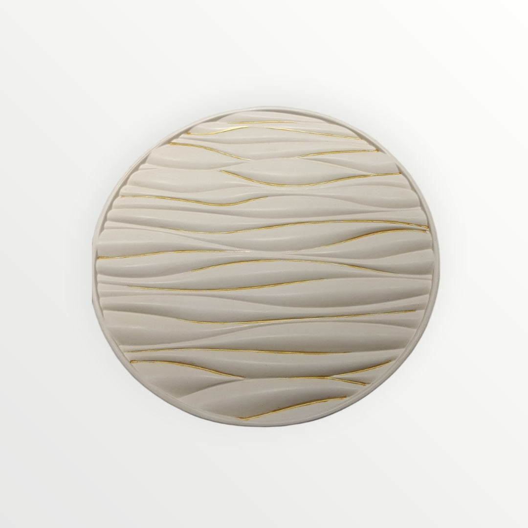 Plato decorativo AIKO circular en color crema con relieve ondulado y detalles en líneas doradas, estilo contemporáneo.