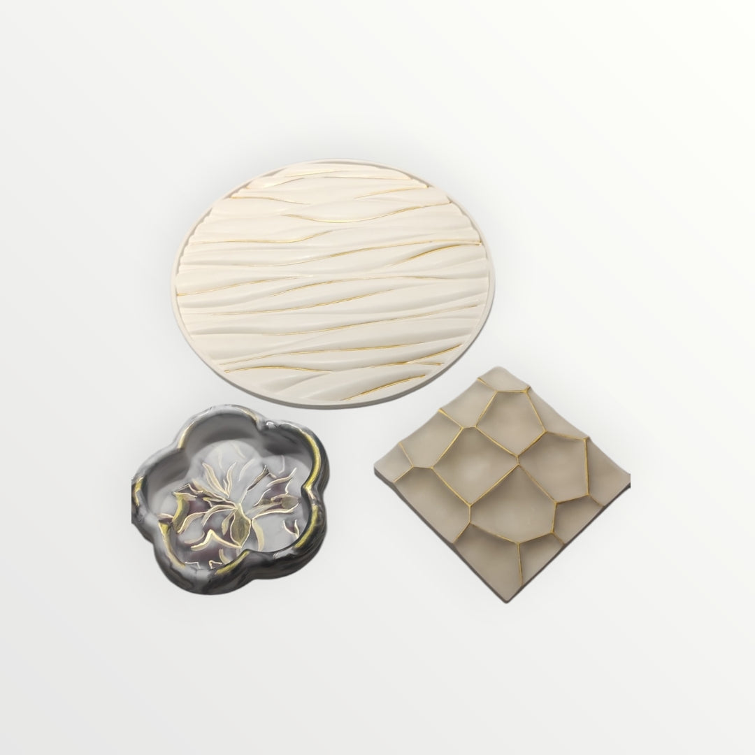 Set de tres platos decorativos AIKO con relieves geométricos y orgánicos en tonos crema, gris y detalles dorados.